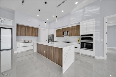 Kitchen with brown cabinetry, modern cabinets, a center island with sink, pendant lighting, and recessed lighting