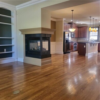 Unfurnished living room with crown molding, built in features, a multi sided fireplace, and dark wood-style floors