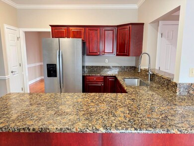 Kitchen featuring crown molding, stainless steel fridge with ice dispenser, reddish brown cabinets, and a sink