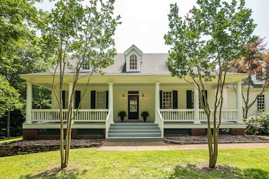View of front of home with a shingled roof, covered porch, and a front yard