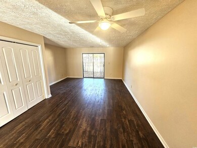 Unfurnished bedroom with ceiling fan, dark hardwoo