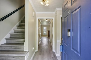 Entryway featuring ornamental molding, a textured ceiling, stairs, light wood finished floors, and a chandelier