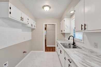 Kitchen with backsplash, sink, and white cabinetry