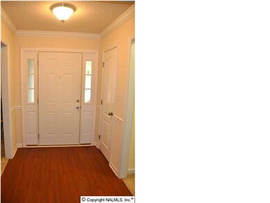 Foyer features hardwood floors, crown molding, and a coat closet
