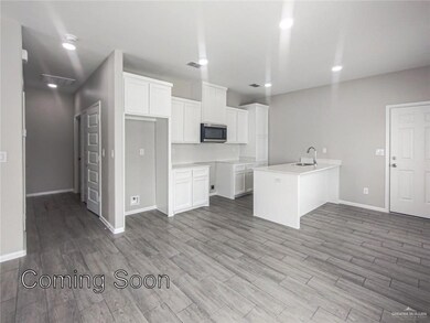 Kitchen featuring stainless steel microwave, white cabinetry, a peninsula, light wood-style floors, and recessed lighting