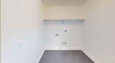 Laundry room with dark tile patterned flooring, washer hookup, and hookup for an electric dryer
