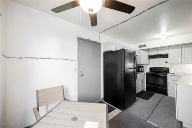 Kitchen with black appliances, light countertops, a ceiling fan, and under cabinet range hood