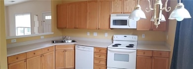 Kitchen featuring white appliances, light countertops, and light brown cabinets