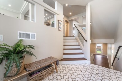 Staircase with high vaulted ceiling and recessed l