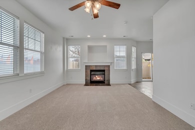 Unfurnished living room with light colored carpet, ceiling fan, a fireplace, and recessed lighting