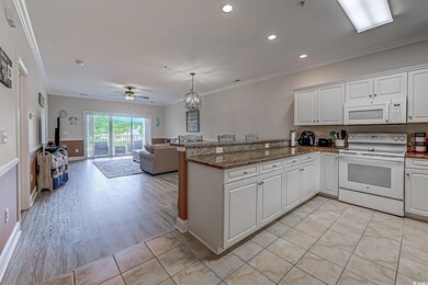 Kitchen with white appliances, a peninsula, ornamental molding, open floor plan, and white cabinets