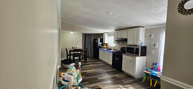 Kitchen with vaulted ceiling, white cabinets, dark