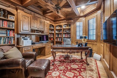 Office-study with lots of built-ins, built-in desk, file cabinets and book shelves & cabinets.  Coffered ceiling and flat screen TV on wall.