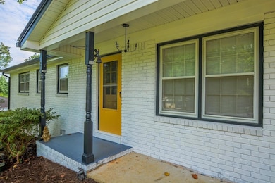 View of exterior entry featuring brick siding and covered porch