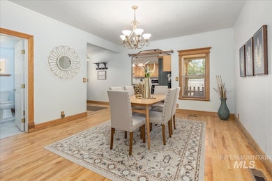 Dining area with a chandelier, wood finished floors, and ornamental molding
