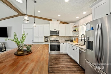 Kitchen featuring appliances with stainless steel finishes, wood counters, open shelves, decorative backsplash, and hanging light fixtures