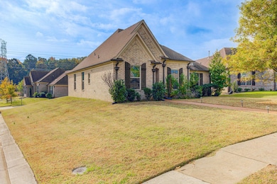 French country inspired facade featuring brick siding, a front yard, and a shingled roof