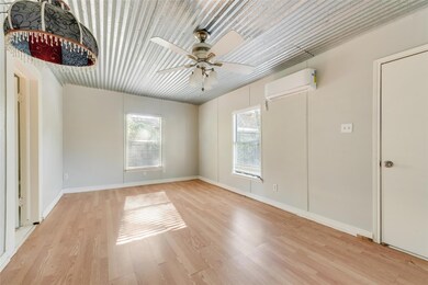 Unfurnished room featuring ceiling fan, light wood-type flooring, and a wall unit AC