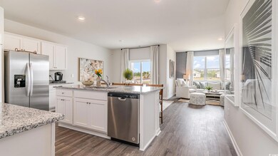 Kitchen with stainless steel appliances, dark wood-type flooring, open floor plan, white cabinetry, and a center island with sink