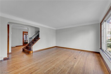 Spare room featuring ornamental molding, plenty of natural light, and light hardwood / wood-style floors