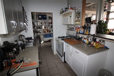 Kitchen with white appliances, white cabinets, dark tile patterned floors, and a peninsula