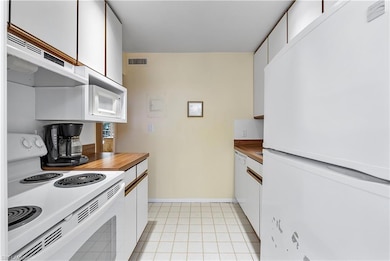 Kitchen with visible vents, white appliances, unde