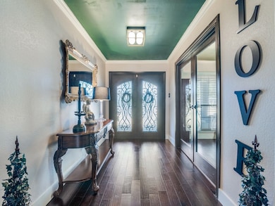 Foyer featuring a textured wall, crown molding, french doors, and dark wood finished floors