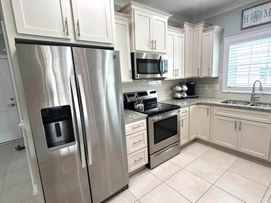 Kitchen featuring appliances with stainless steel finishes, decorative backsplash, light off white countertops, and light tile patterned floors