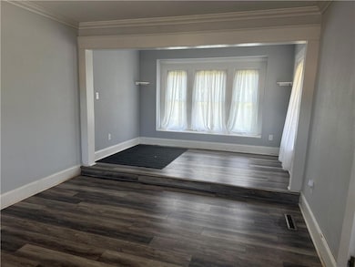 Empty room with ornamental molding and dark wood-style floors