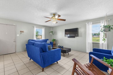 Living room featuring ceiling fan, a textured ceiling, and light tile floors
