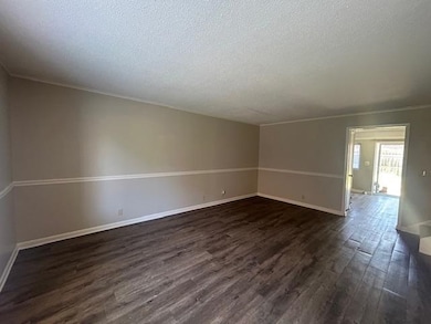 Empty room featuring dark wood-style floors and a textured ceiling