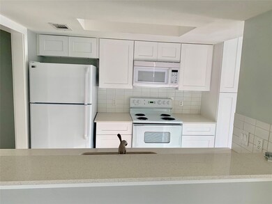 Kitchen featuring white appliances, white cabinets, and decorative backsplash