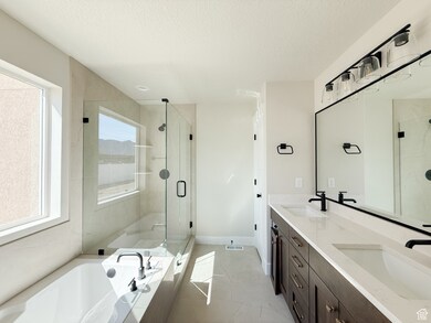 Full bathroom featuring a shower stall, double vanity, a bath, light tile patterned floors, and a textured ceiling