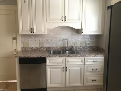 Kitchen featuring stone counters, backsplash, white cabinets, and stainless steel dishwasher