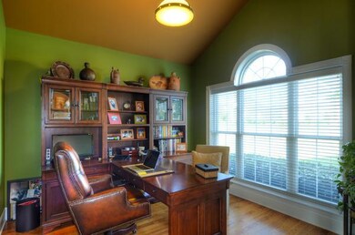 The formal living room is currently being utilized as an elegant office space with cathedral ceiling and designer colors.