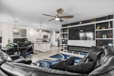 Living area with ceiling fan, light wood finished floors, a chandelier, and recessed lighting