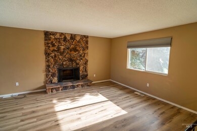 Unfurnished living room with a textured ceiling, wood finished floors, and a fireplace