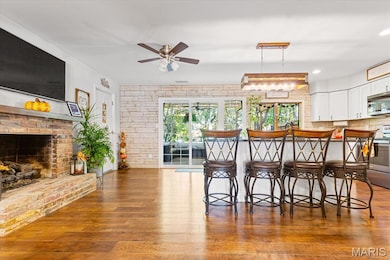 Dining room featuring light wood-style flooring, ceiling fan, a fireplace, and recessed lighting