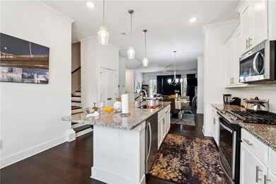 Kitchen featuring appliances with stainless steel finishes, dark wood-type flooring, a kitchen island with sink, light stone counters, and recessed lighting
