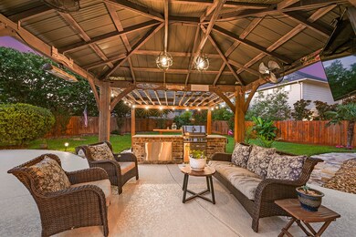The outdoor pergola showcases a stunning stained design and includes an outdoor grilling setup, complete with a ceiling fan and lighting. This blend of natural elements and modern amenities creates an inviting and comfortable outdoor space, ideal for enjoying evenings with family and friends throughout the year.