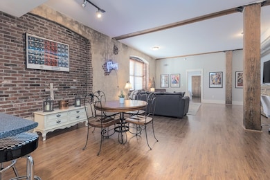 Dining room featuring wood finished floors, brick wall, and baseboards