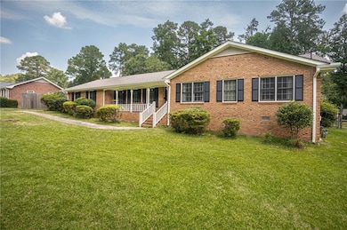 Ranch-style home with brick siding, a front lawn, and a porch