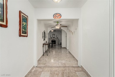 Corridor with baseboards, arched walkways, and a t