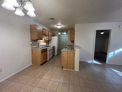 Kitchen with light countertops, white appliances, a textured ceiling, a chandelier, and hanging light fixtures