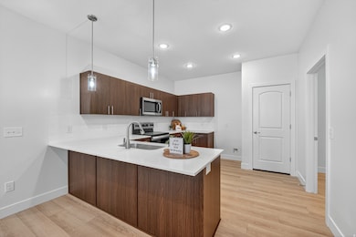 Elevated kitchen with dark wood tone cabinets, quartz counters, tile backsplash, and stainless steel appliances.