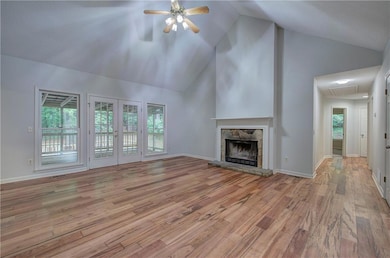 Unfurnished living room with a ceiling fan, wood finished floors, attic access, healthy amount of natural light, and high vaulted ceiling