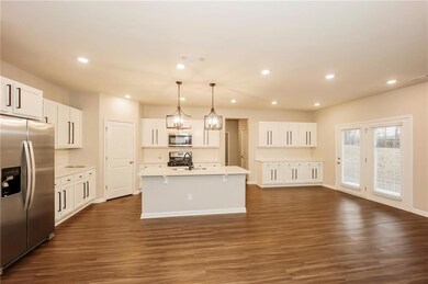 Kitchen featuring appliances with stainless steel finishes, a sink, backsplash, dark wood-style flooring, and light countertops