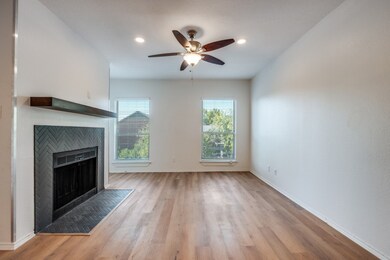 Unfurnished living room featuring a tiled fireplace, light wood-type flooring, and ceiling fan