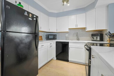 Kitchen featuring black appliances, white cabinets, backsplash, and ornamental molding
