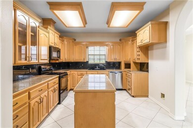 Kitchen featuring black appliances, glass insert cabinets, backsplash, tile countertops, and a center island